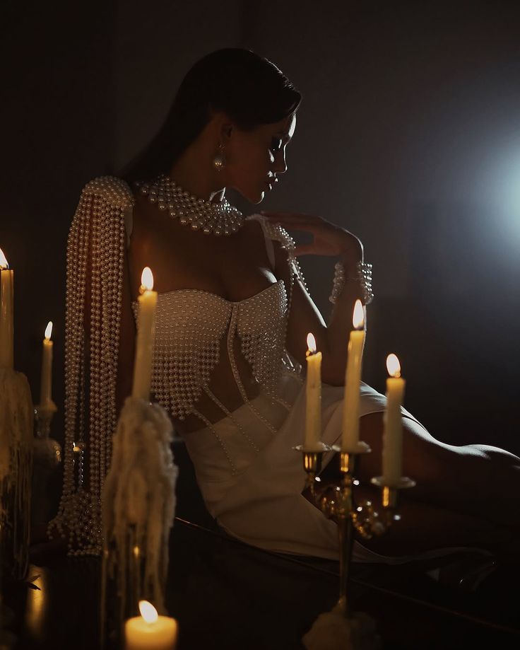 A woman in pearls among candles